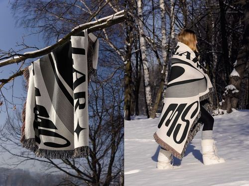 Winter-themed mockup of a jacquard woven blanket with abstract black and white design, displayed in a snowy forest setting.