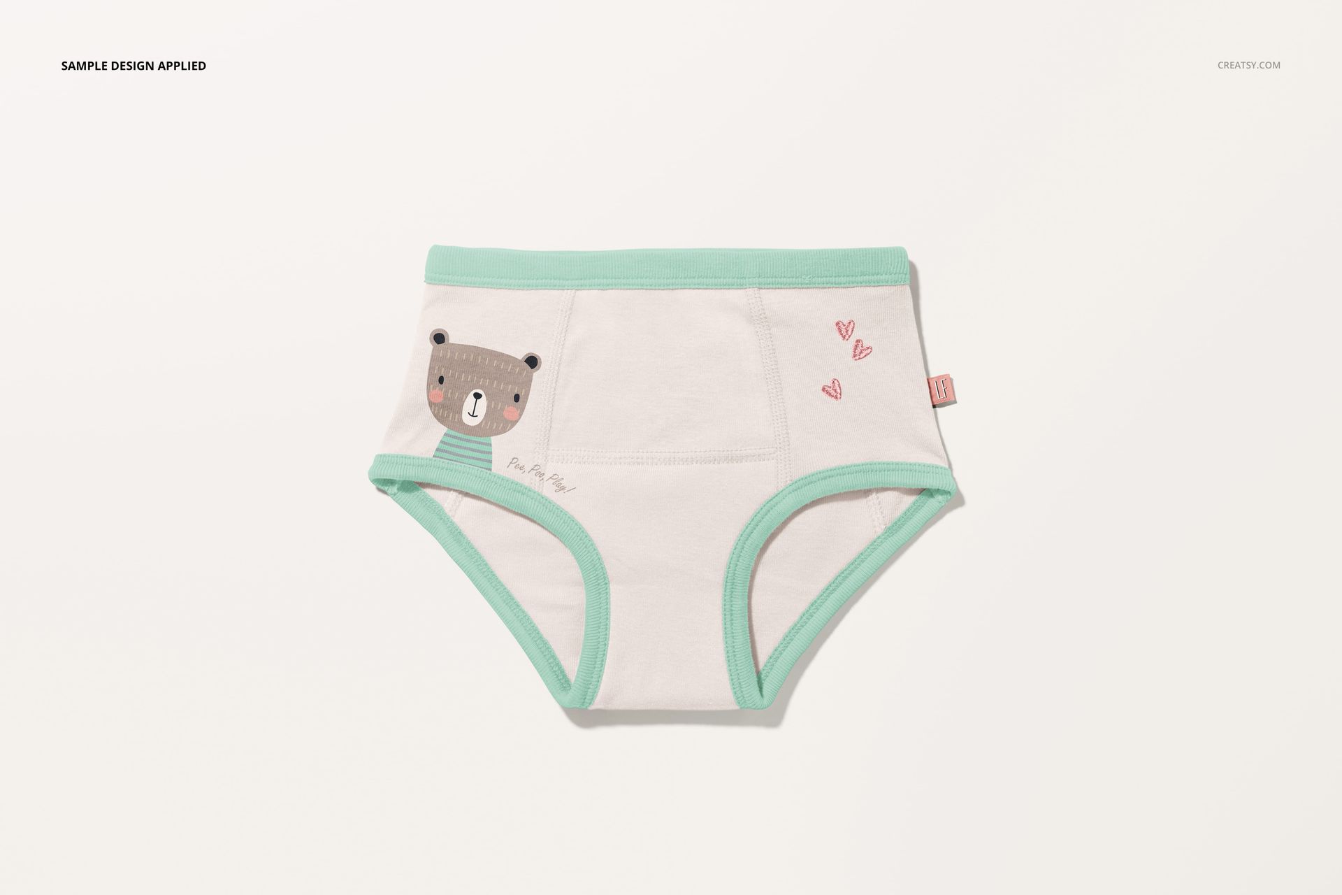 Front view of toddler training pants mockup featuring mint edges, bear graphic, and small pink hearts.