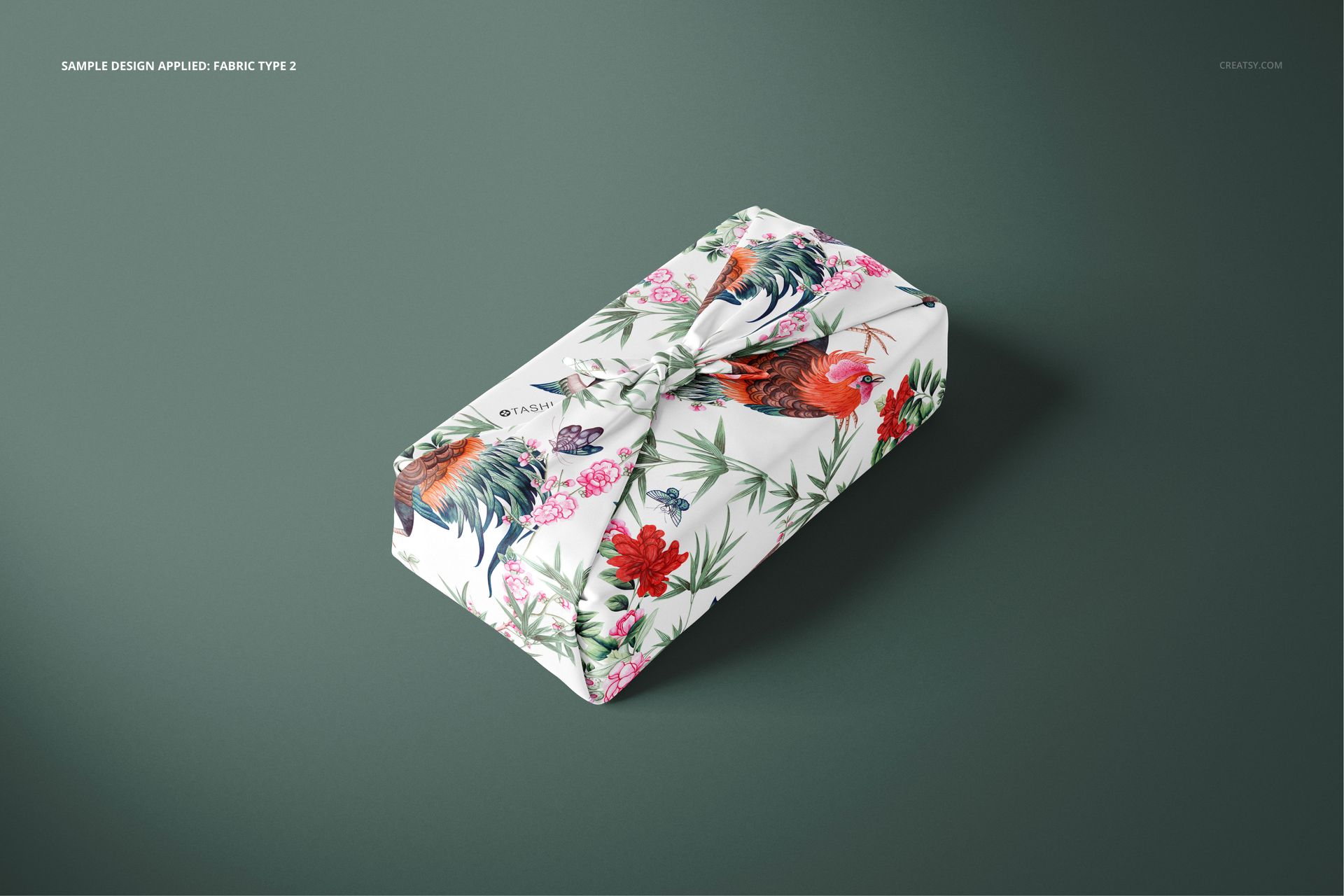 Furoshiki fabric wrap mockup featuring a colorful rooster and floral design, shown from a slightly elevated front view.