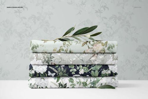 PSD mockup showing layered jersey fabrics in various botanical prints, stacked horizontally with olive branch accents on top.