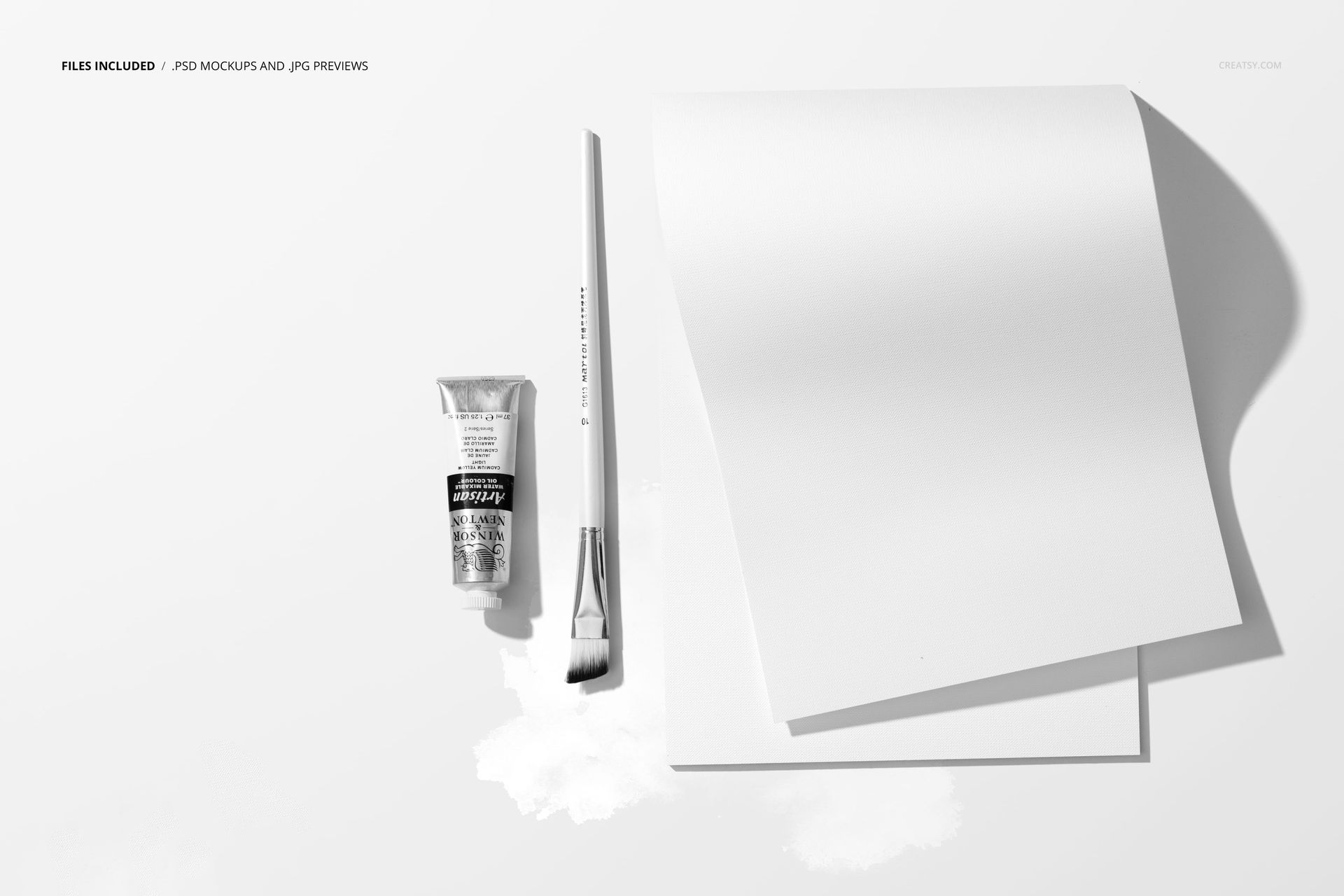 Top view of a decorative paper pad mockup with a paintbrush and a tube of paint on a white surface.
