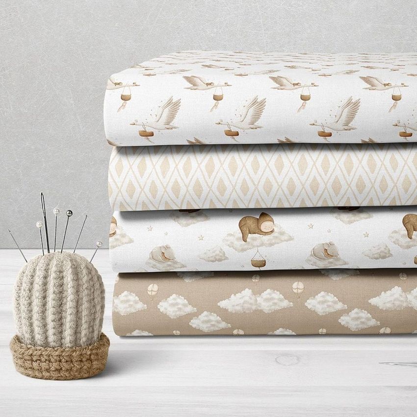 Folded fabrics mockup featuring four stacked textiles with whimsical baby-themed patterns in beige and white tones on a light surface.