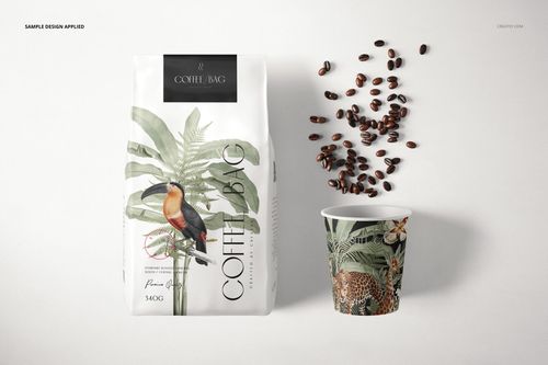 Front view of a paper coffee bag mockup with tropical bird and plant design, next to a coffee cup and scattered beans.
