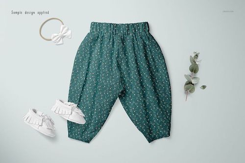 Baby lantern harem pants mockup displayed flat with green floral print, white shoes, headband, and eucalyptus sprig.