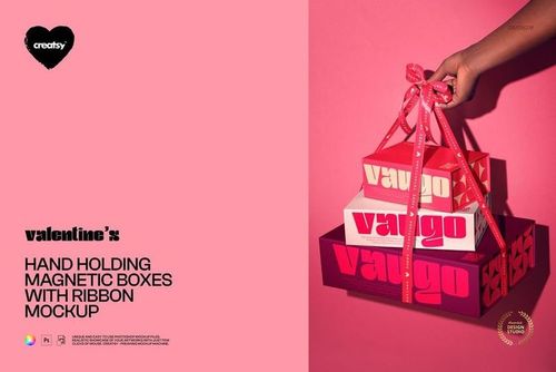 Stack of magnetic packaging boxes with ribbon, held by a hand, showcasing a PSD mockup on a vibrant pink backdrop.