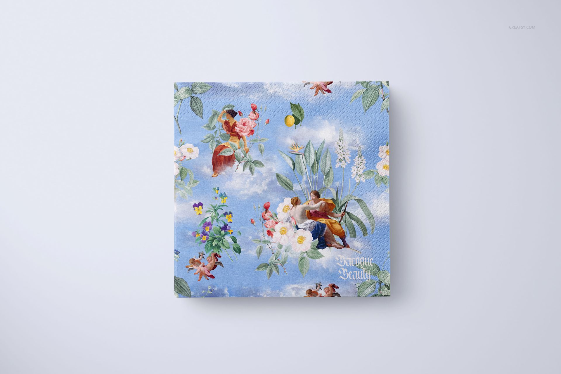 Decorative napkin mockup featuring blue sky, flowers, and cherubs, displayed flat against a light surface.
