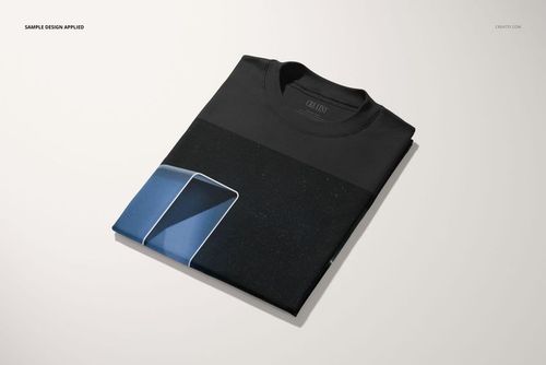 Folded oversized t-shirt mockup in black with a geometric blue and white pattern, displayed on a plain surface.