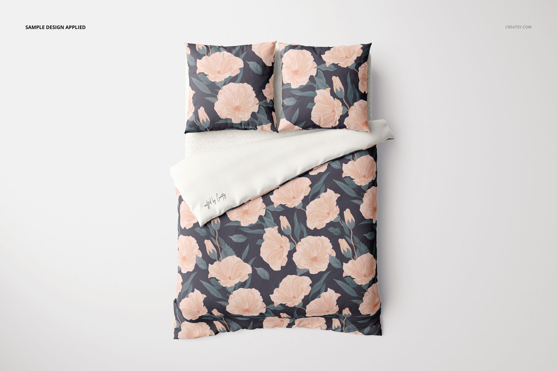Bedding mockup with euro pillows and blanket, displaying large peach flowers and green leaves from an overhead angle.