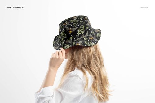 Reversible bucket hat mockup featuring a dark leafy design, modeled by a person with long blonde hair in a white shirt.