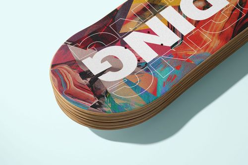 Close-up view of a skateboard deck with layered wood edges and vibrant abstract artwork on the top surface.