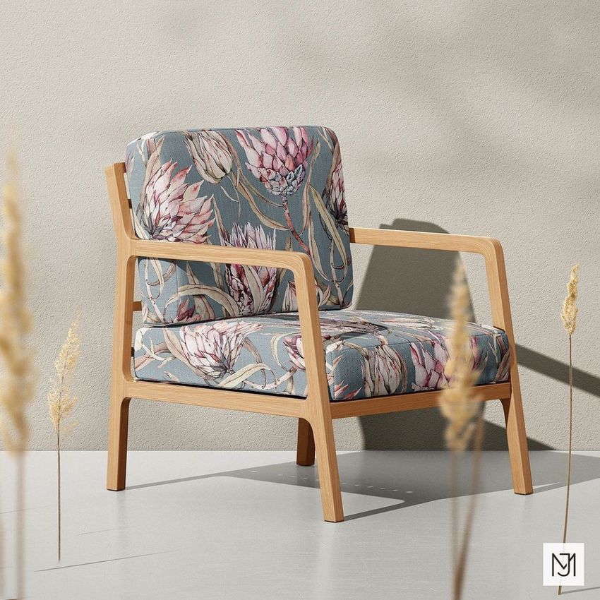Lounge chair mockup with light wood frame and cushions featuring a botanical protea pattern on a muted blue background.