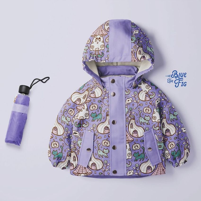 Kids rainwear mockup featuring a hooded jacket with purple panels and whimsical pumpkin and dinosaur patterns, shown from above.
