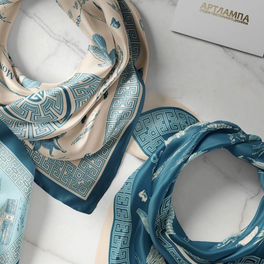 Silk scarf mockup featuring two folded scarves with intricate blue and beige patterns on a marble surface, with a card nearby.