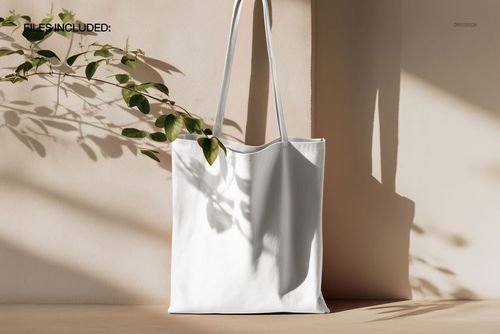 PSD mockup of a simple canvas tote bag in a minimal setting, featuring natural light and plant shadow details.