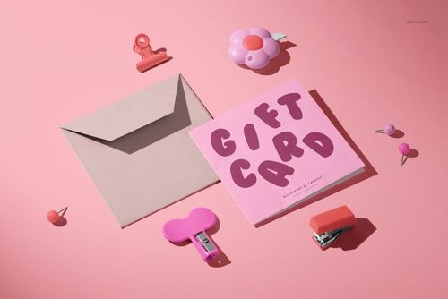 PSD mockup of a square greeting card and envelope arranged with pink stationery items on a light pink surface.