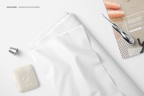 White fabric bolt displayed with sewing accessories such as thread spools, thimble, and a sewing guide in a mockup scene.
