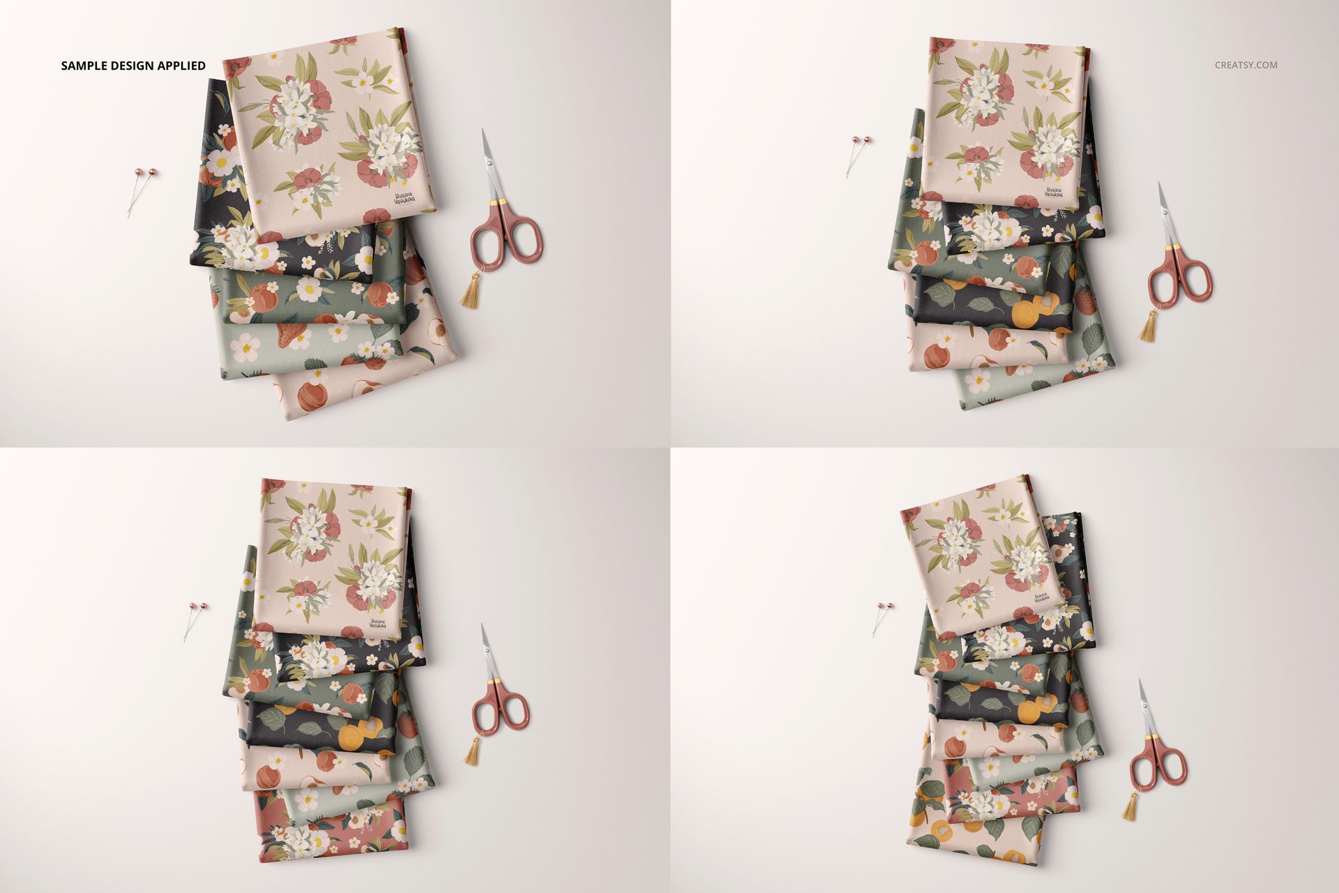 Folded fabrics mockup showing multiple stacks with botanical designs, viewed from above, scissors as props on a neutral surface.