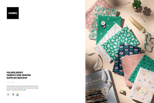 Folded jersey fabrics in green, pink, and patterned designs arranged on a wooden surface with sewing supplies nearby.