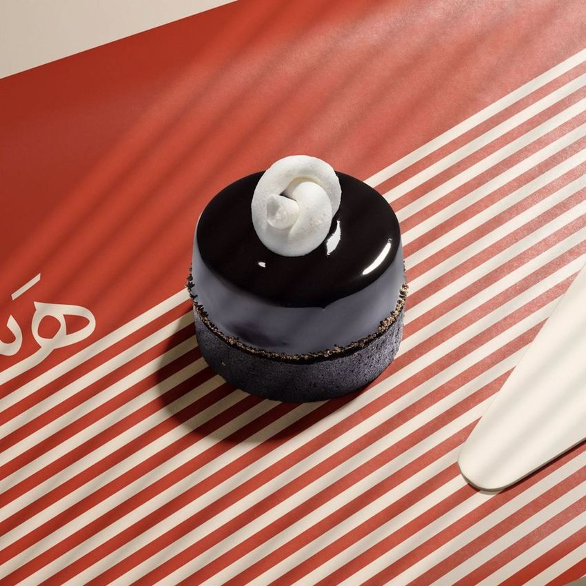 Food safe paper mockup featuring a glossy chocolate dessert with white topping placed on striped red and cream wrapping paper.