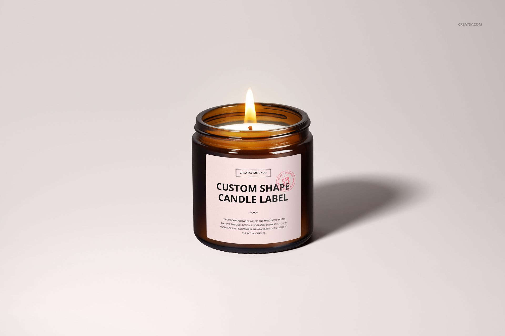 Amber glass jar candle with a cotton wick, burning on a light background, shown in a front view mockup.