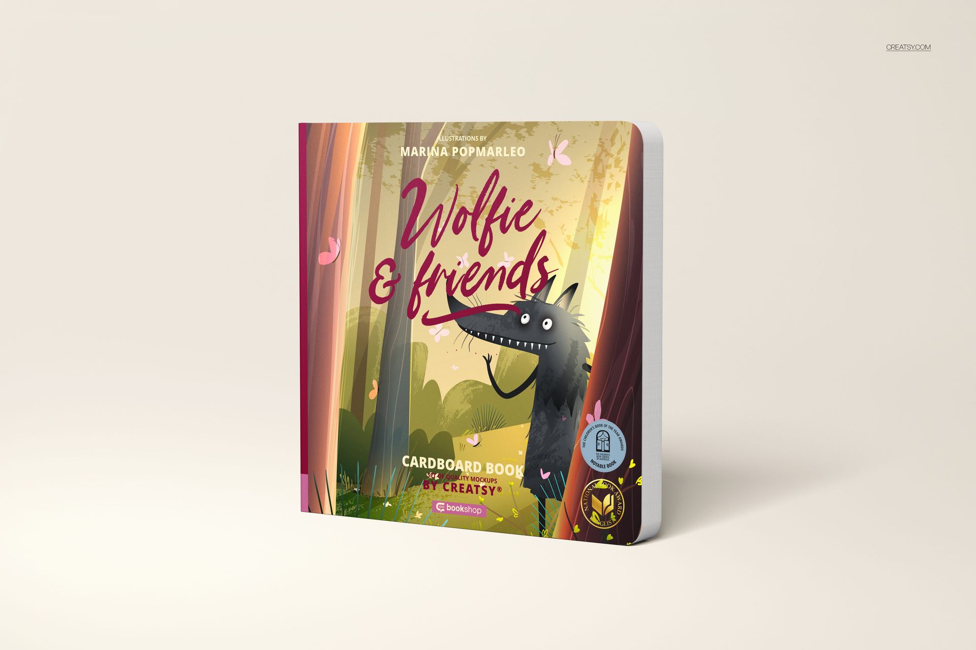 Front view of a cardboard baby book mockup with colorful artwork of a wolf and trees, standing upright on a plain surface.