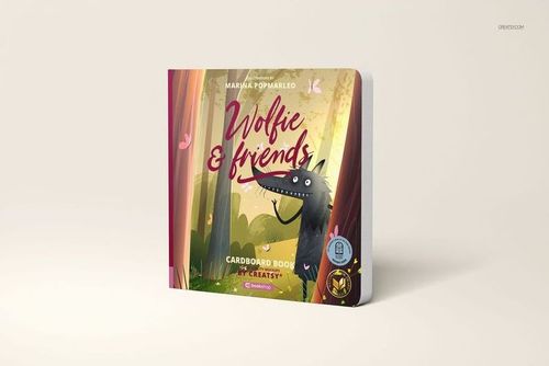 Front view of a cardboard baby book mockup with colorful artwork of a wolf and trees, standing upright on a plain surface.