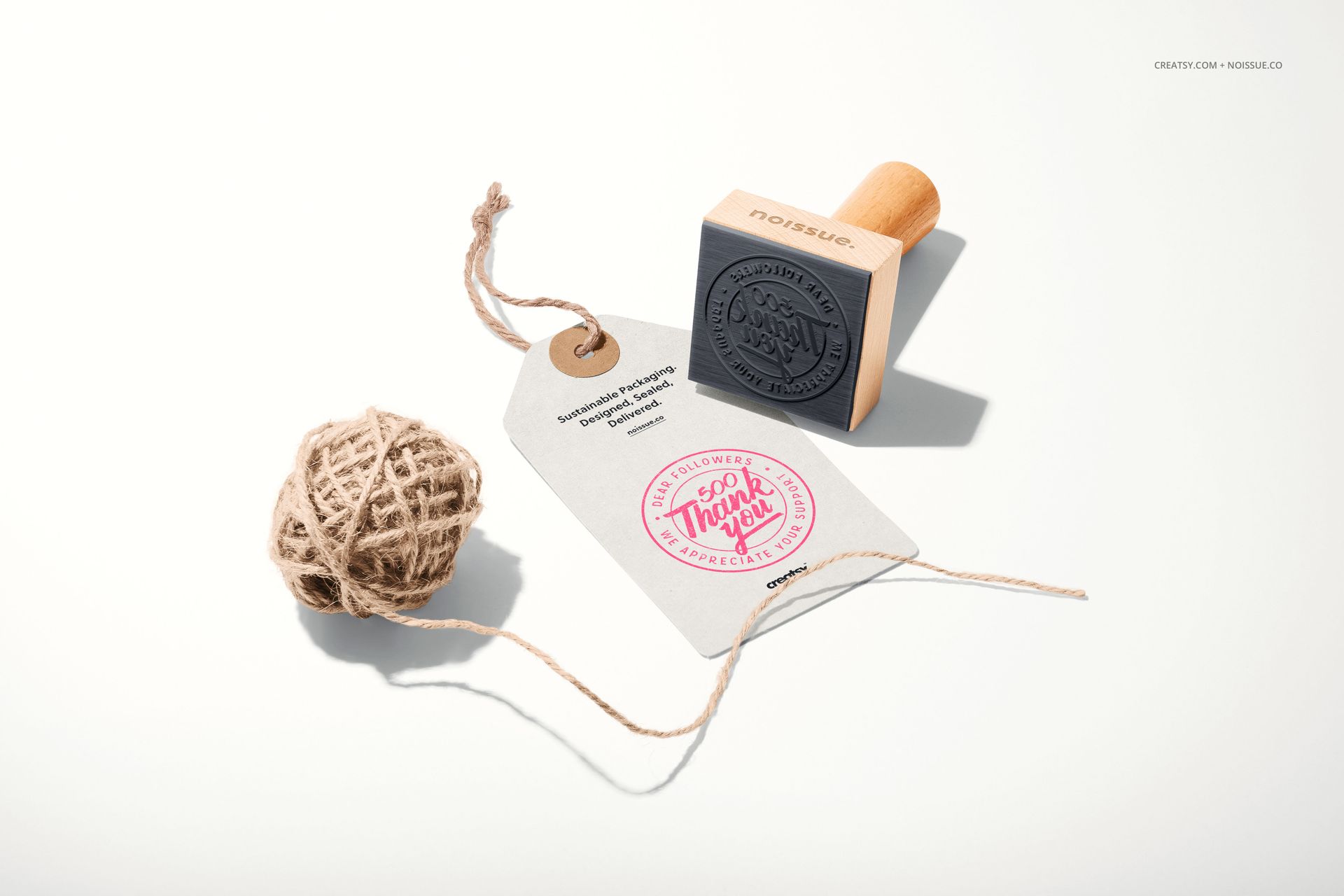 Noissue wooden stamp mockup set featuring a stamp, kraft paper tag with pink imprint, and twine, top view.