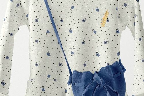 Front view of a baby dress mockup with long sleeves, white fabric, blue floral pattern, and small navy bag accessory.
