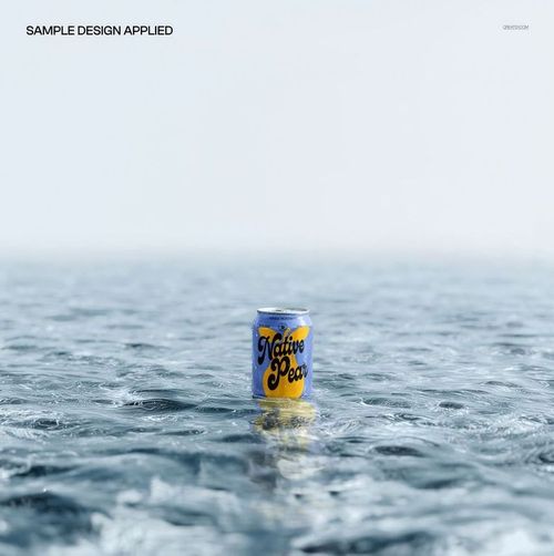 Beverage can with a blue and yellow design standing upright on a calm water surface, front view mockup.