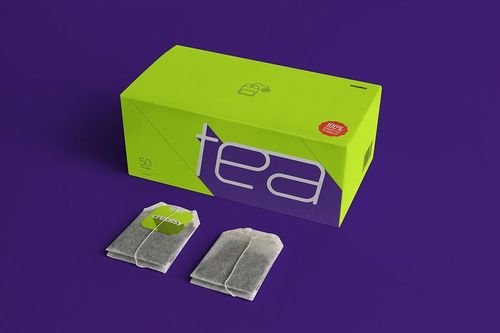 Tea packaging mockup featuring a green box with large text and two tea bags displayed in front, set against a purple background.