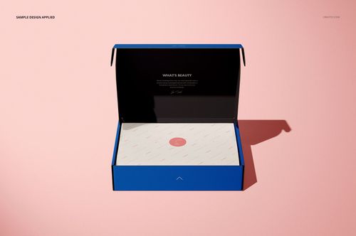 Open mailing box mockup with blue exterior and black lid, white patterned insert, shown from a top angle on pink surface.