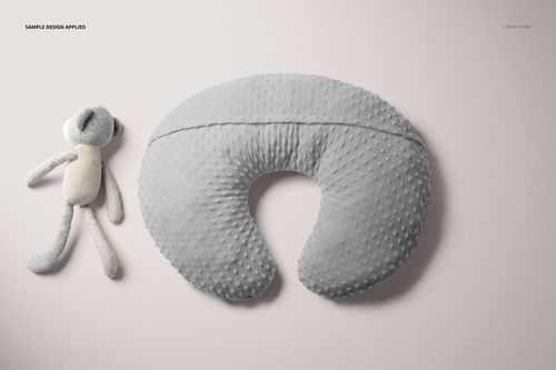 PSD mockup featuring a gray nursing pillow cover with raised dots, accompanied by a fabric stuffed animal on a neutral backdrop.