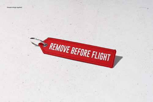 Red fabric keychain mockup featuring bold white lettering, placed on a neutral background with a metal ring attached.