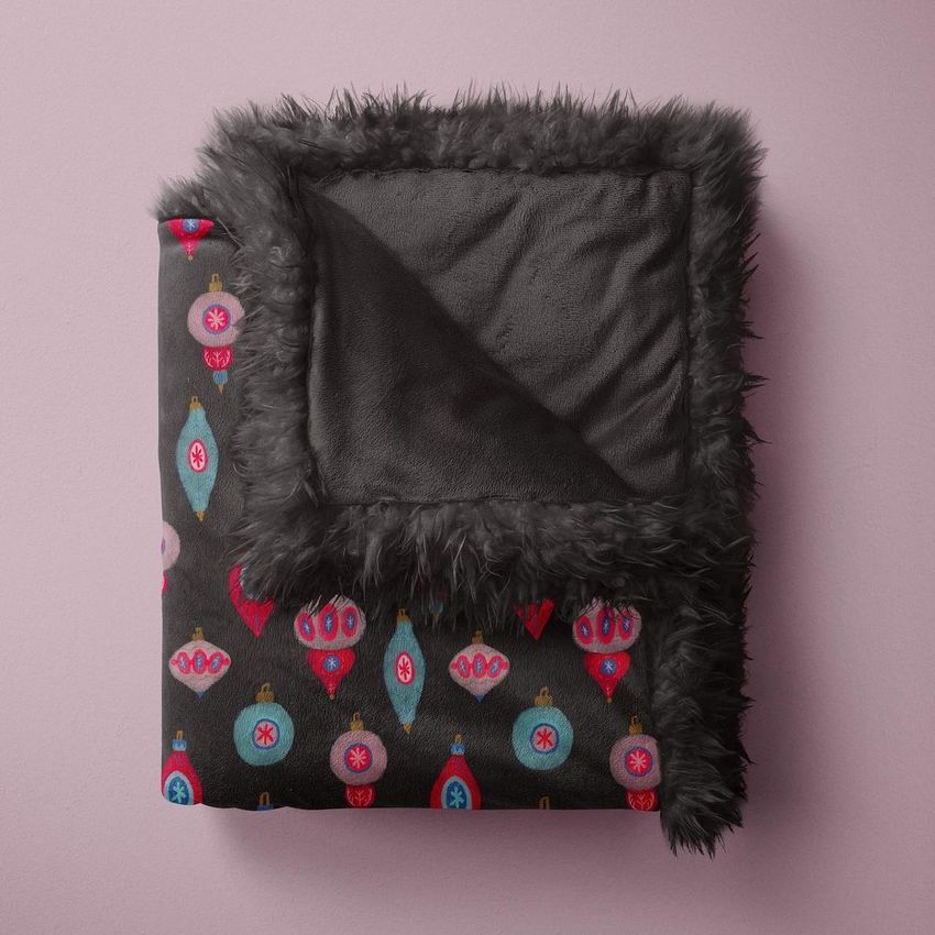 Sherpa baby blanket mockup featuring a folded black blanket with colorful retro ornament patterns on a soft pink background.