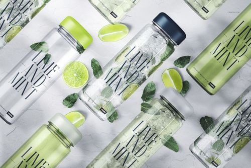 PSD mockup of transparent water bottles with assorted lid colors, surrounded by fresh lime slices and mint leaves.