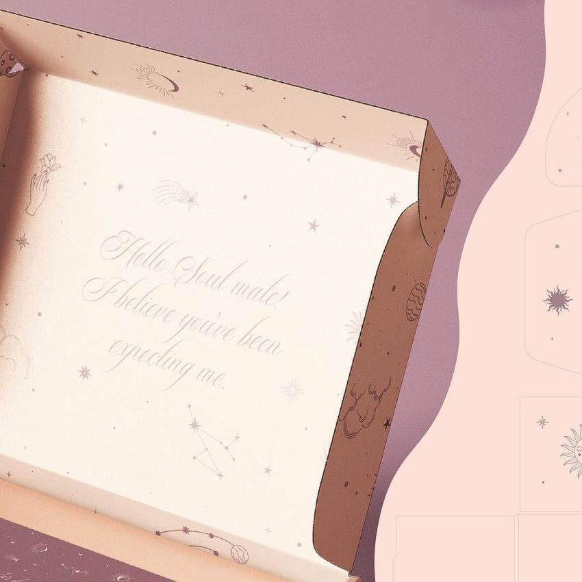 Mailing box mockup with celestial illustrations on the inner flaps and handwritten text printed inside, photographed on a pink surface.