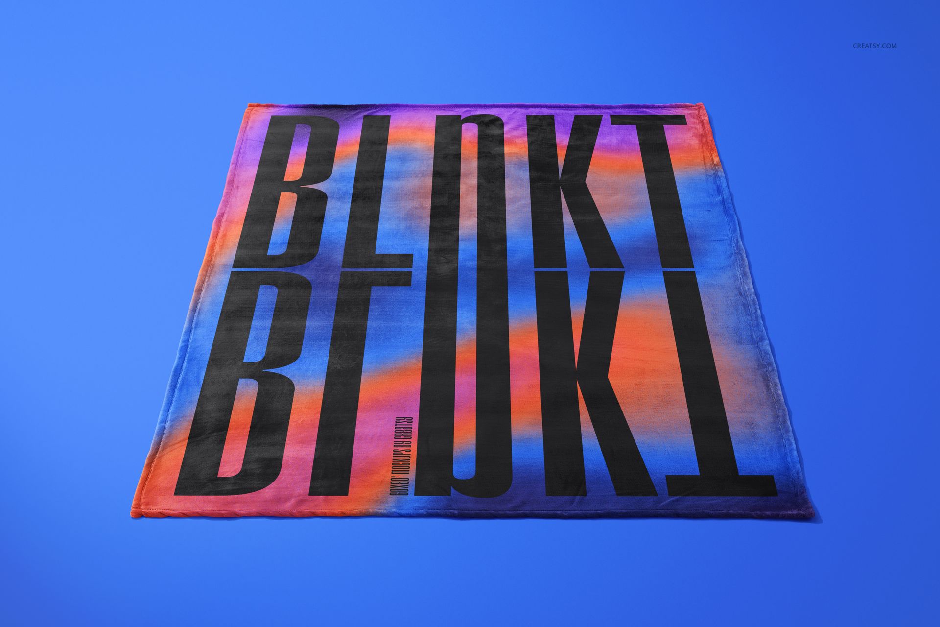 Front view of a fleece blanket mockup featuring large black text and vibrant orange, blue, and purple hues on a blue surface.