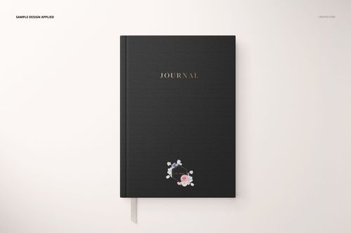 Stationery set mockup featuring a black journal with gold text and small floral design, shown from above.