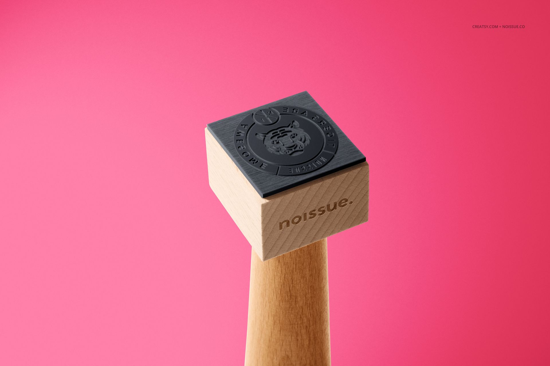Single wooden stamp mockup with engraved black rubber surface, displayed upright on a pink backdrop in close view.