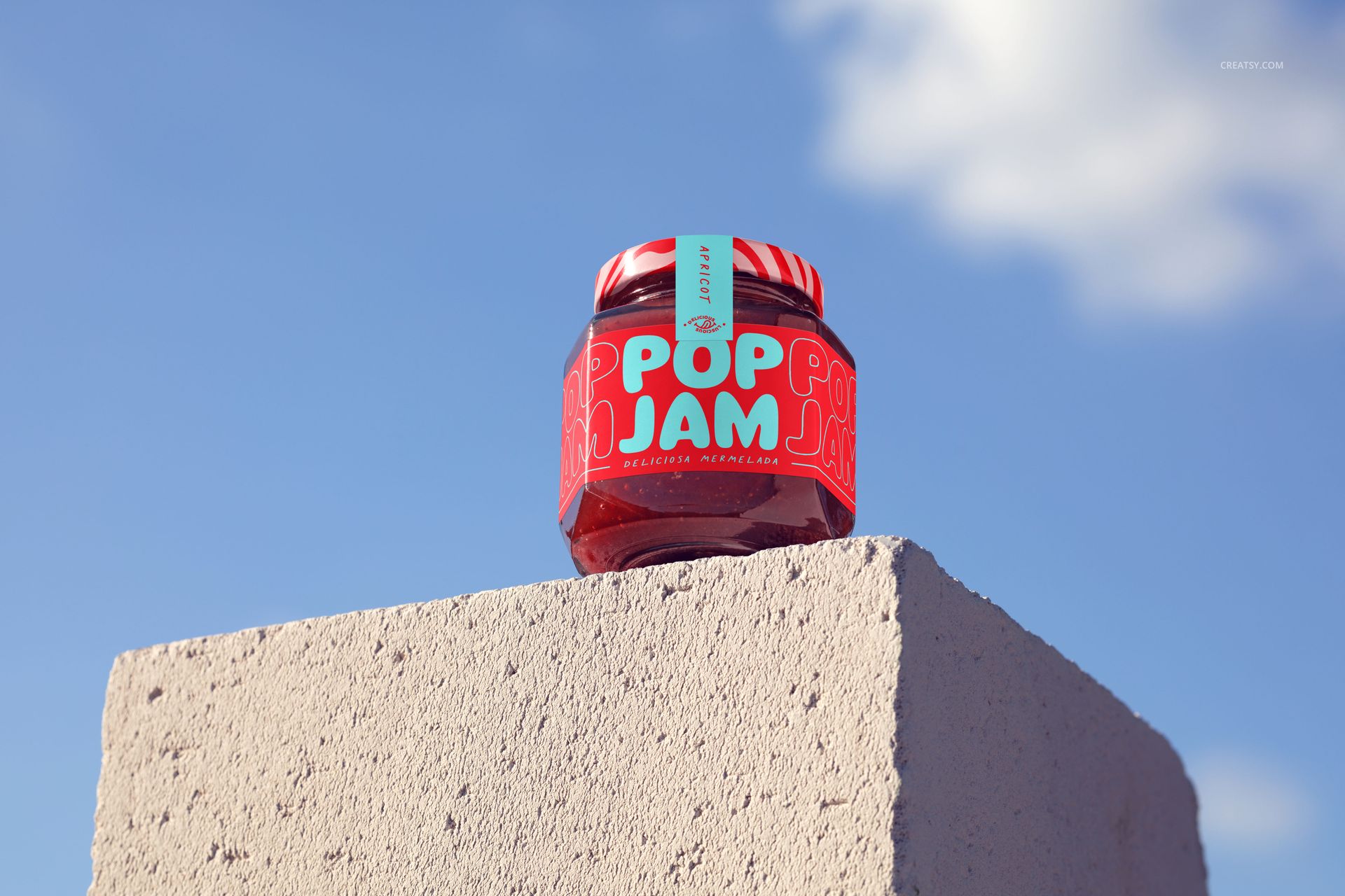 Front view of a jam jar mockup featuring a colorful label, sitting on a textured concrete block against a blue sky.