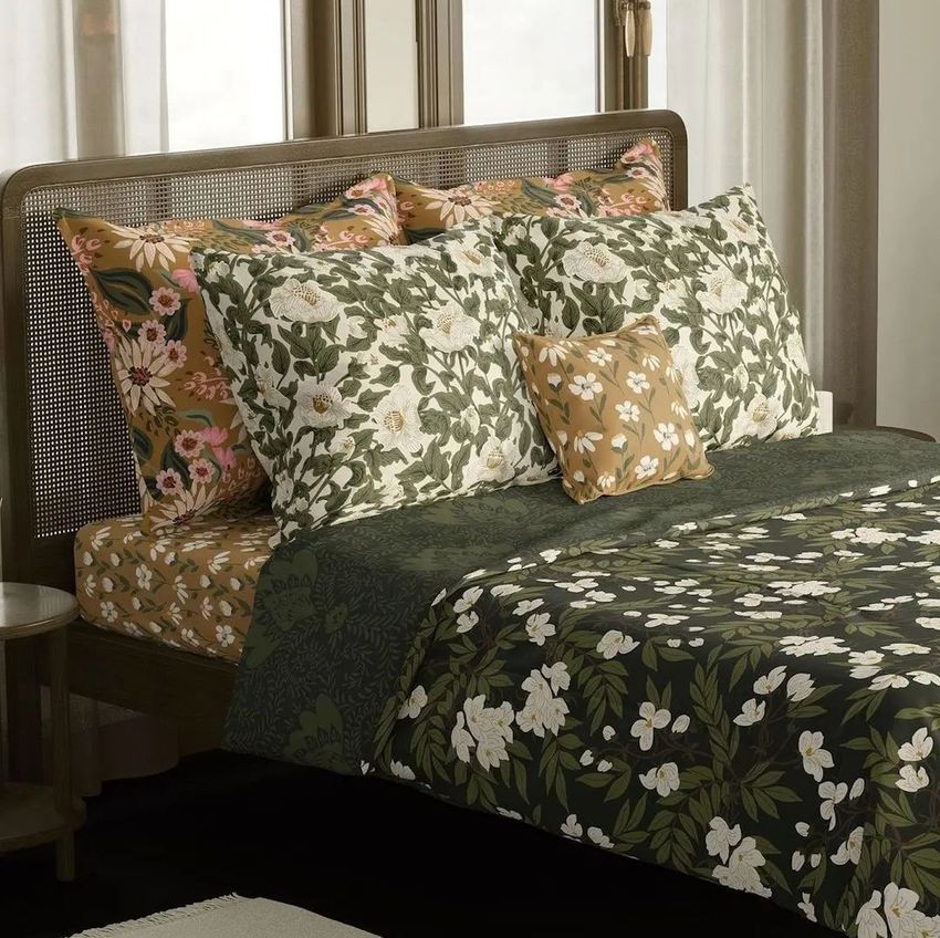 Boho bedroom bedding mockup featuring a bed with floral-patterned pillows and duvet in green, white, and beige tones.