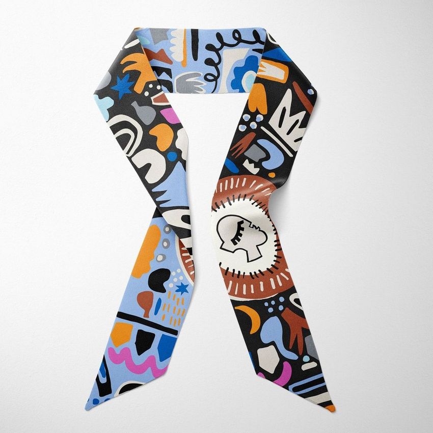 Top view of a twilly scarf mockup featuring bold abstract patterns in black, blue, and orange on a light background.