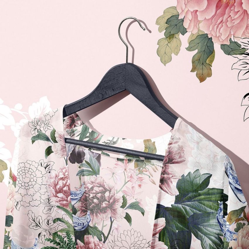 Chiffon kimono mockup featuring a floral pattern, displayed on a black hanger against a pale pink background with floral accents.