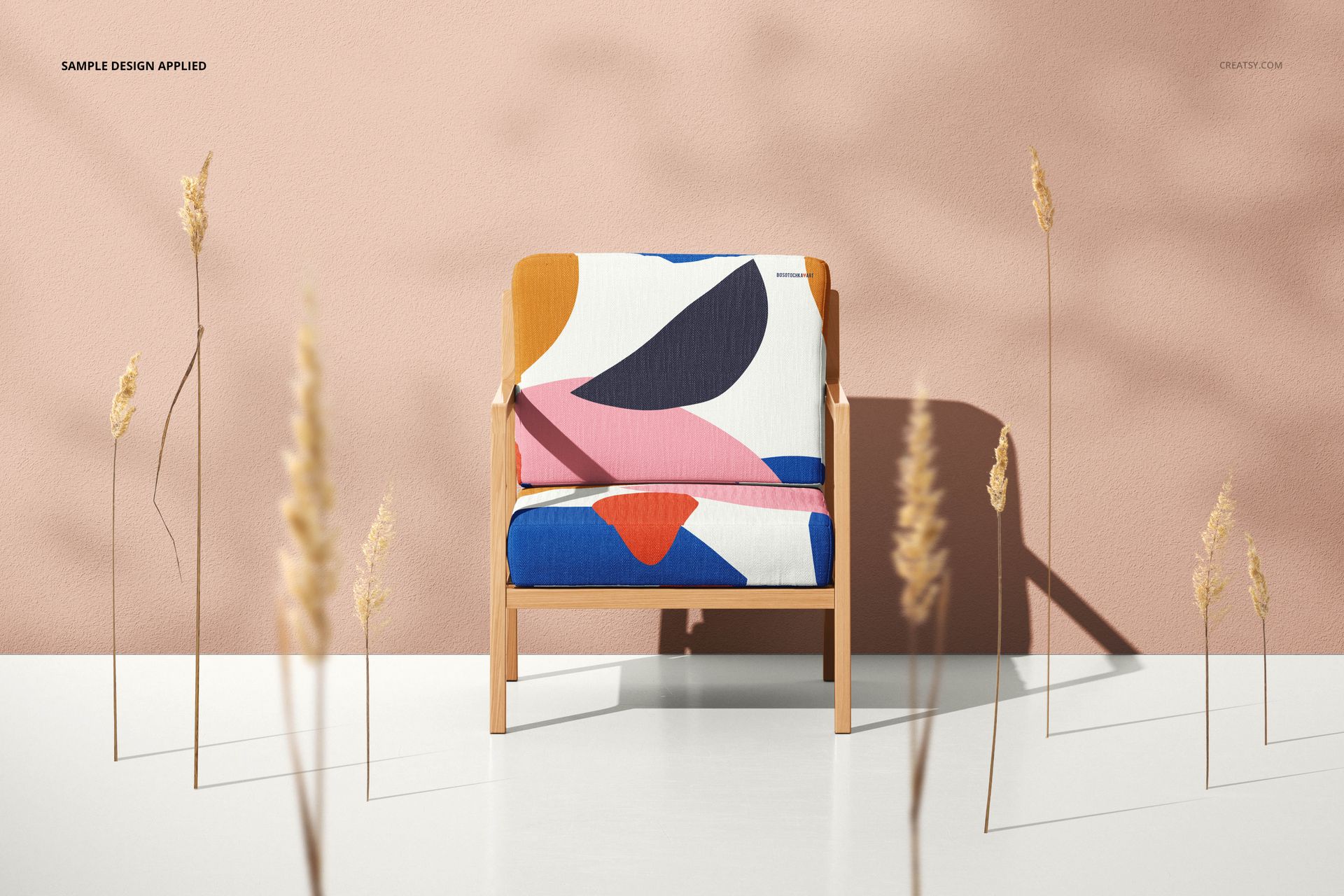 Lounge chair mockup featuring bold geometric shapes in blue, orange, and pink, surrounded by tall dried plants.