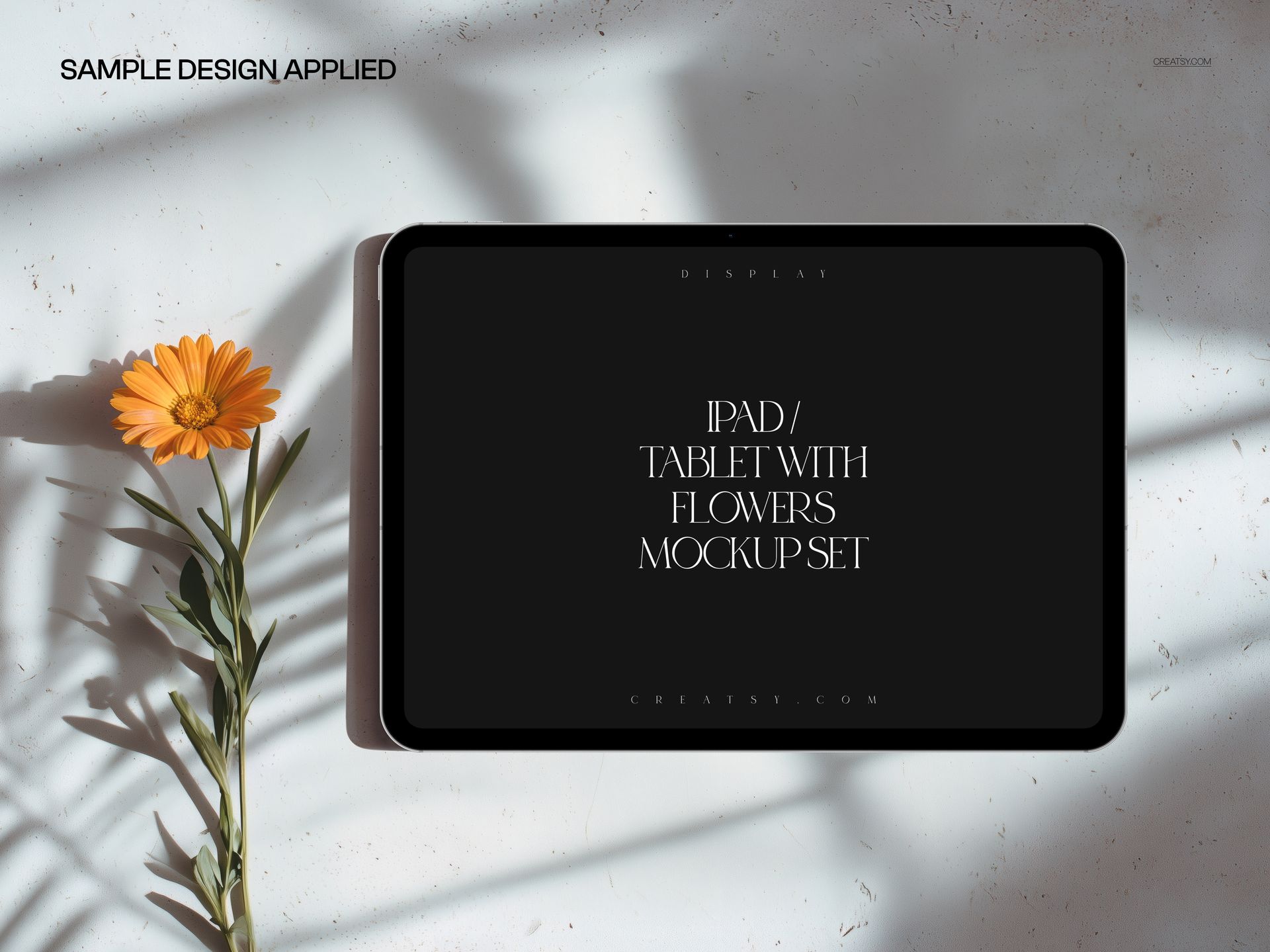 iPad Pro PSD mockup showing a tablet with a black display and orange flower, viewed from above on a white background.