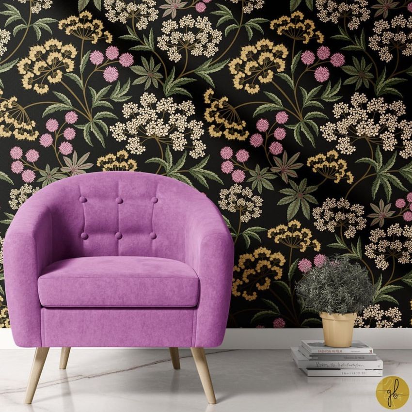 Interior scene mockup featuring a pink armchair in front of a wall with a floral pattern on a dark background, marble floor, and a small plant on stacked books.