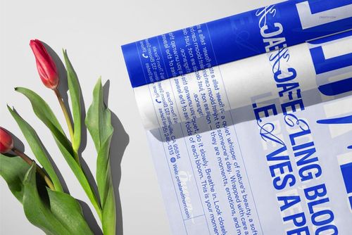 PSD mockup displaying tulip flowers alongside tissue wrapping paper with prominent blue typography, viewed from above.