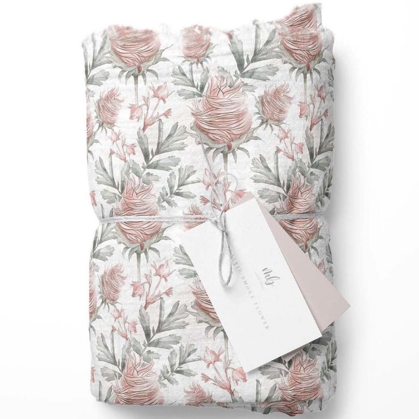 Muslin swaddle blanket mockup featuring a folded fabric with a pink and green floral pattern, tied with string and a blank tag.