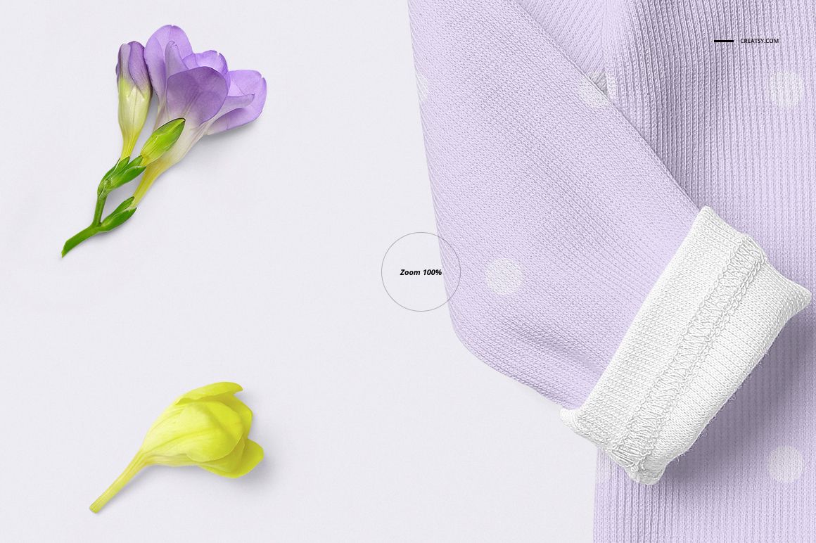PSD mockup showing a baby romper in light purple with white dots and cuff, placed beside purple and yellow flowers.