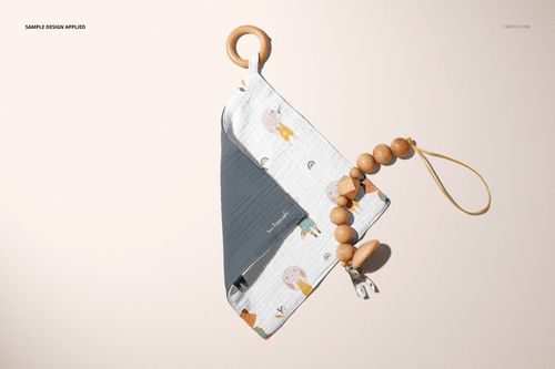 PSD mockup of a muslin swaddle and wooden teether set, displayed flat with soft colors and a simple background.